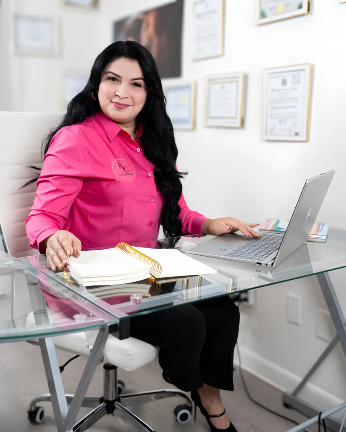 Rosmery Cárdenas sentada en su escritorio en Kissimmee, con sus certificaciones enmarcadas en la pared.