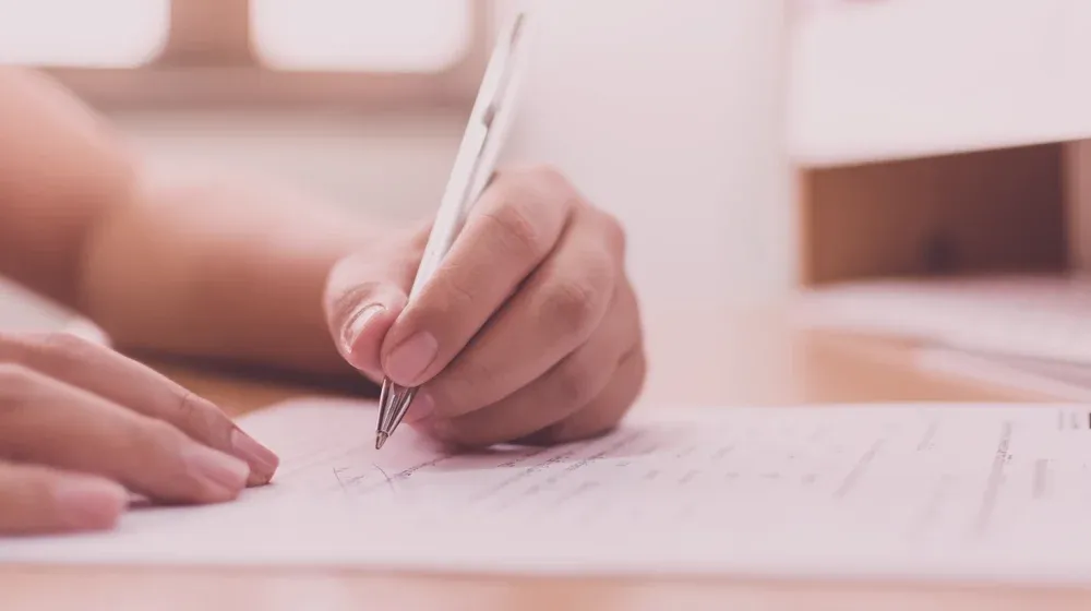Una mano firmando un documento de constitución de empresa.